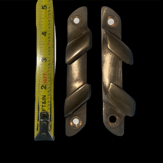 Two metallic door handles with a tape measure for scale on a black background
