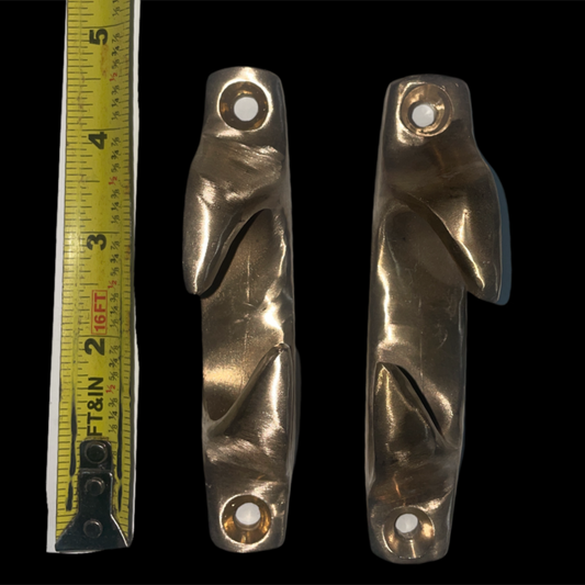 Two brass door handles with a ruler for scale on a black background