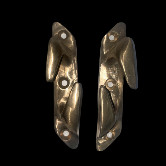 Pair of gold-colored metal hooks on a black background