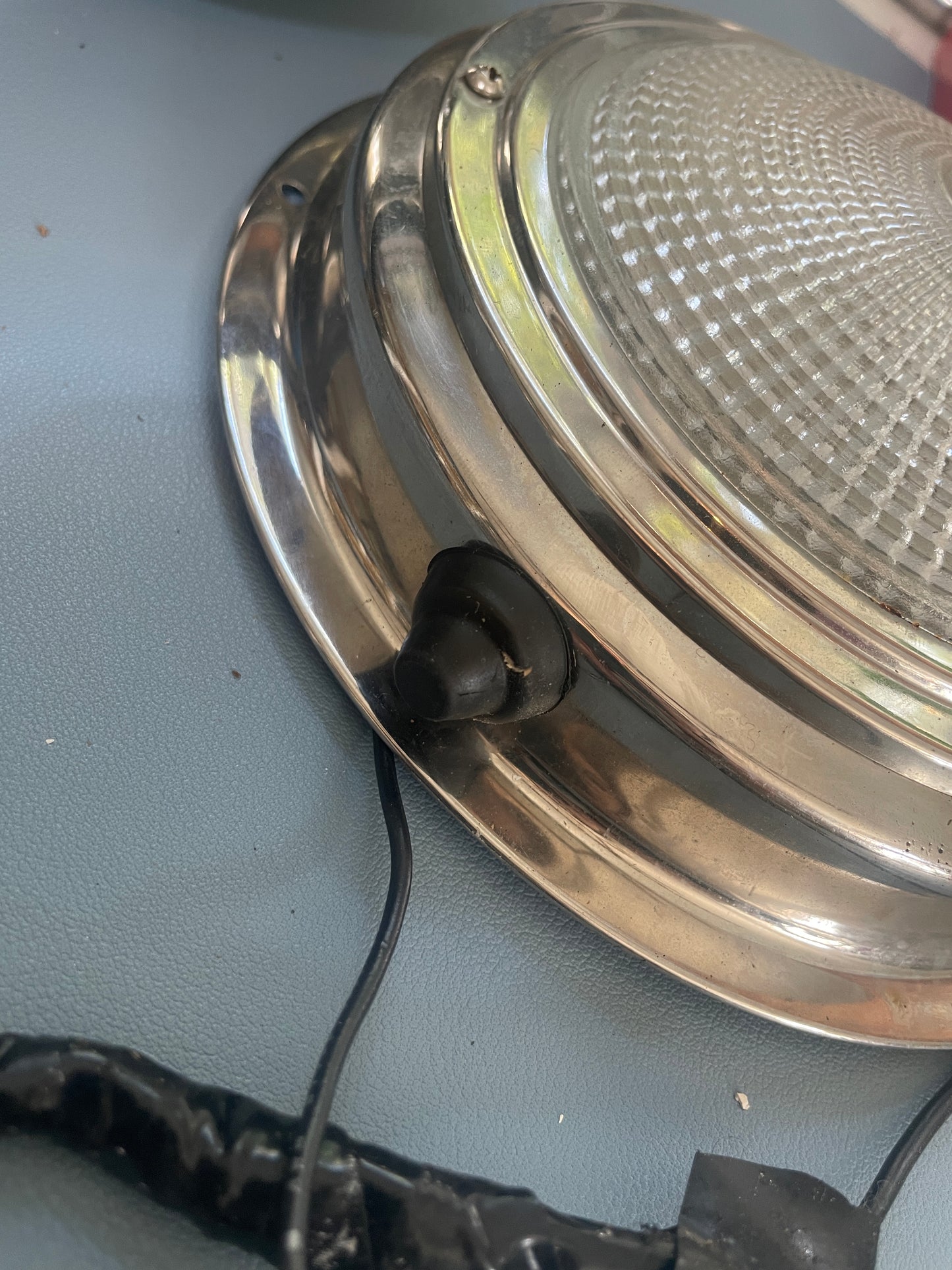 Metallic lampshade with a black cord on a gray surface