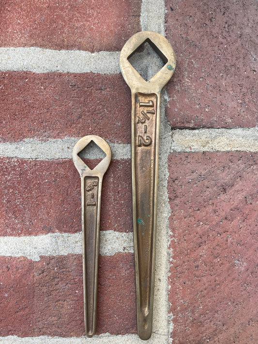 Two brass wrenches on a brick surface