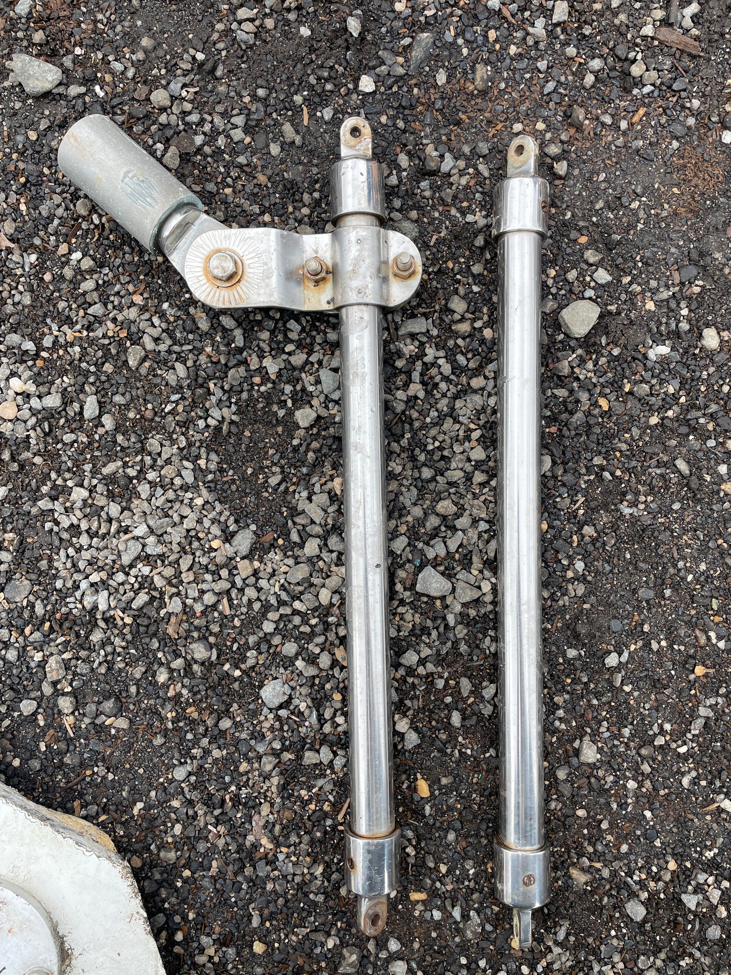 Two metal shock absorbers on a concrete surface