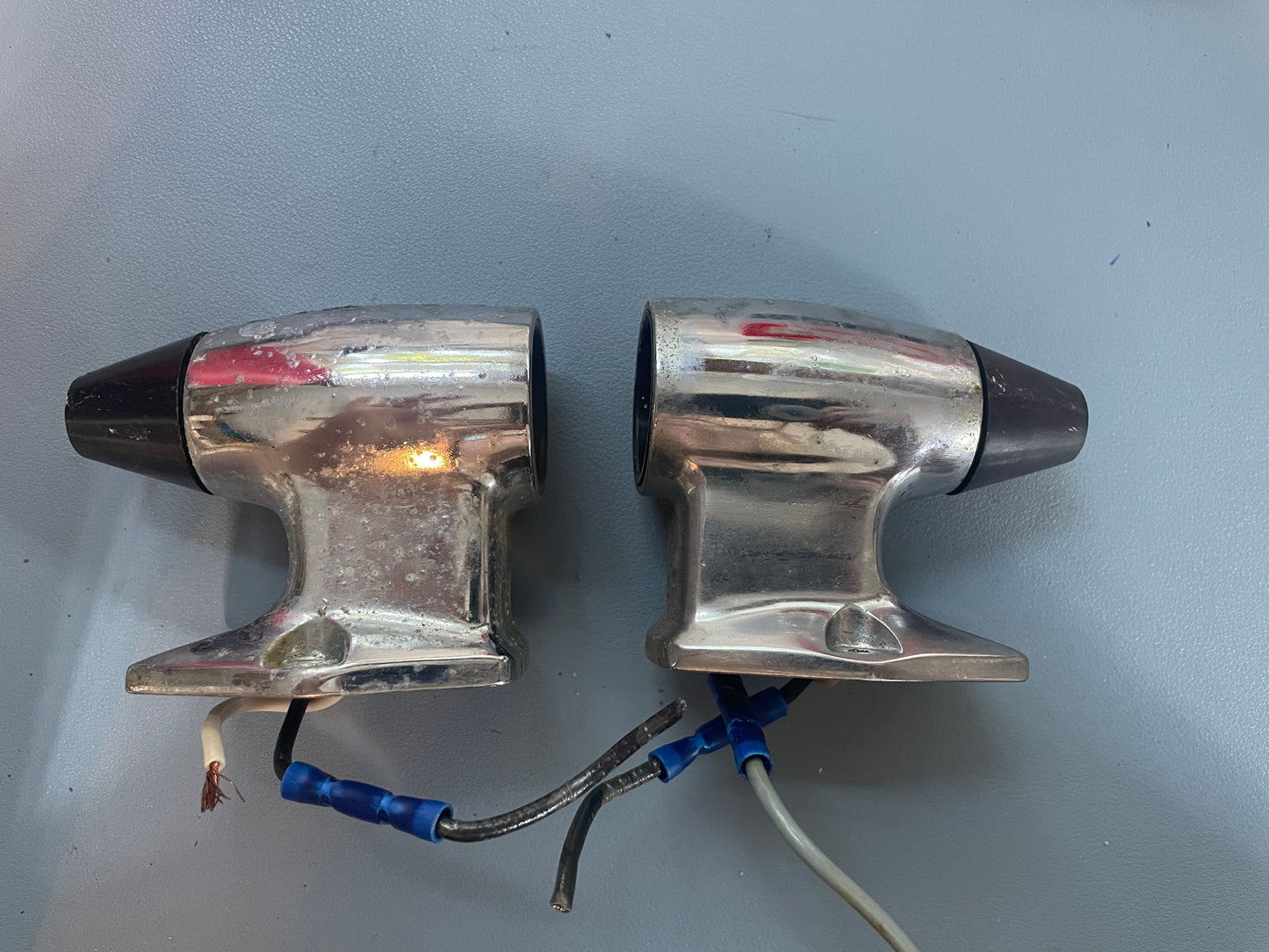 Two metallic car headlights with wiring on a gray background
