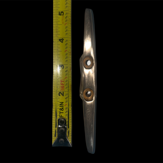 Metal wing tip with a ruler for scale on a black background