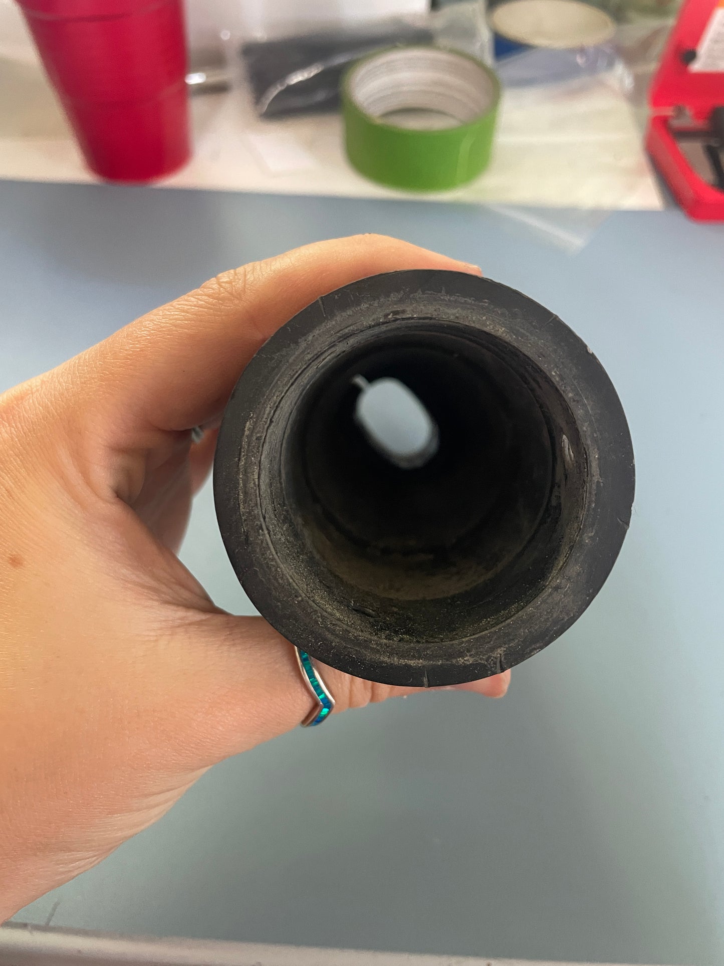 Hand holding a black rubber gasket against a blurred background