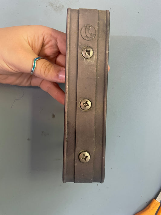 Metal strip with screws held by a hand against a gray background