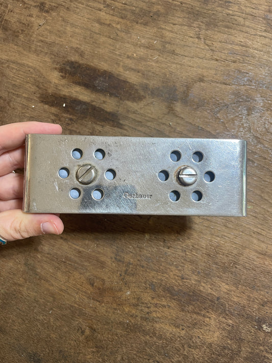 Metal door handle plate held by a hand on a wooden surface