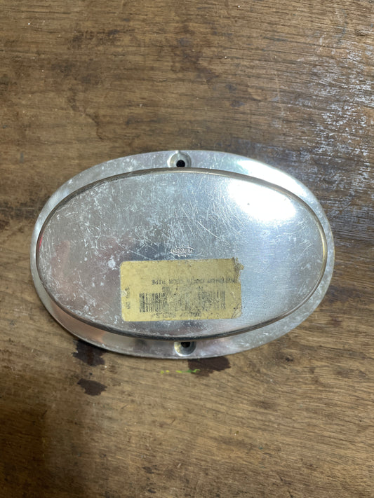 Metallic oval object with a yellow label on a wooden surface