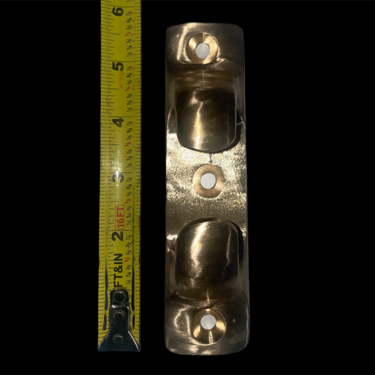 Brass door handle with a tape measure for scale on a black background
