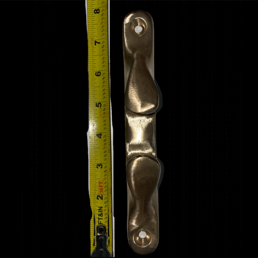 Metallic cleat with a tape measure for scale on a black background