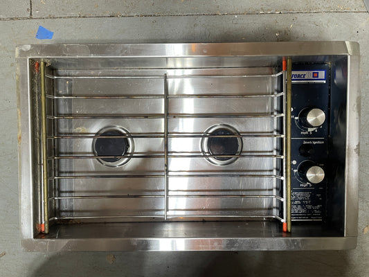 Stainless steel commercial oven with two burners on a concrete floor