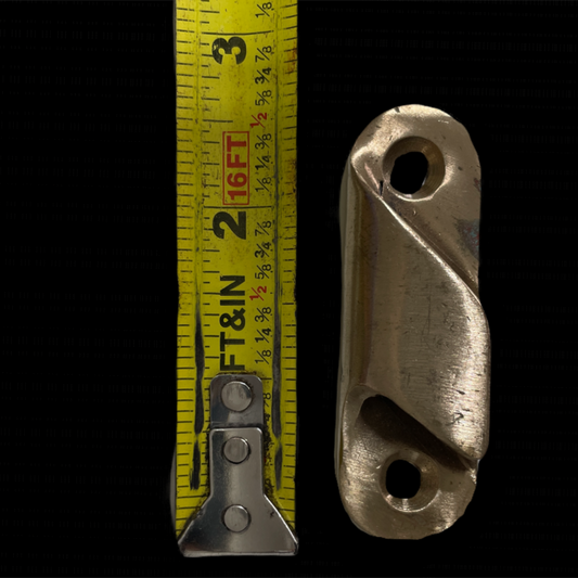 Metal clevis with a tape measure for scale on a black background