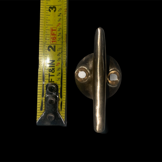 Metal toggle with a measuring tape for scale on a black background