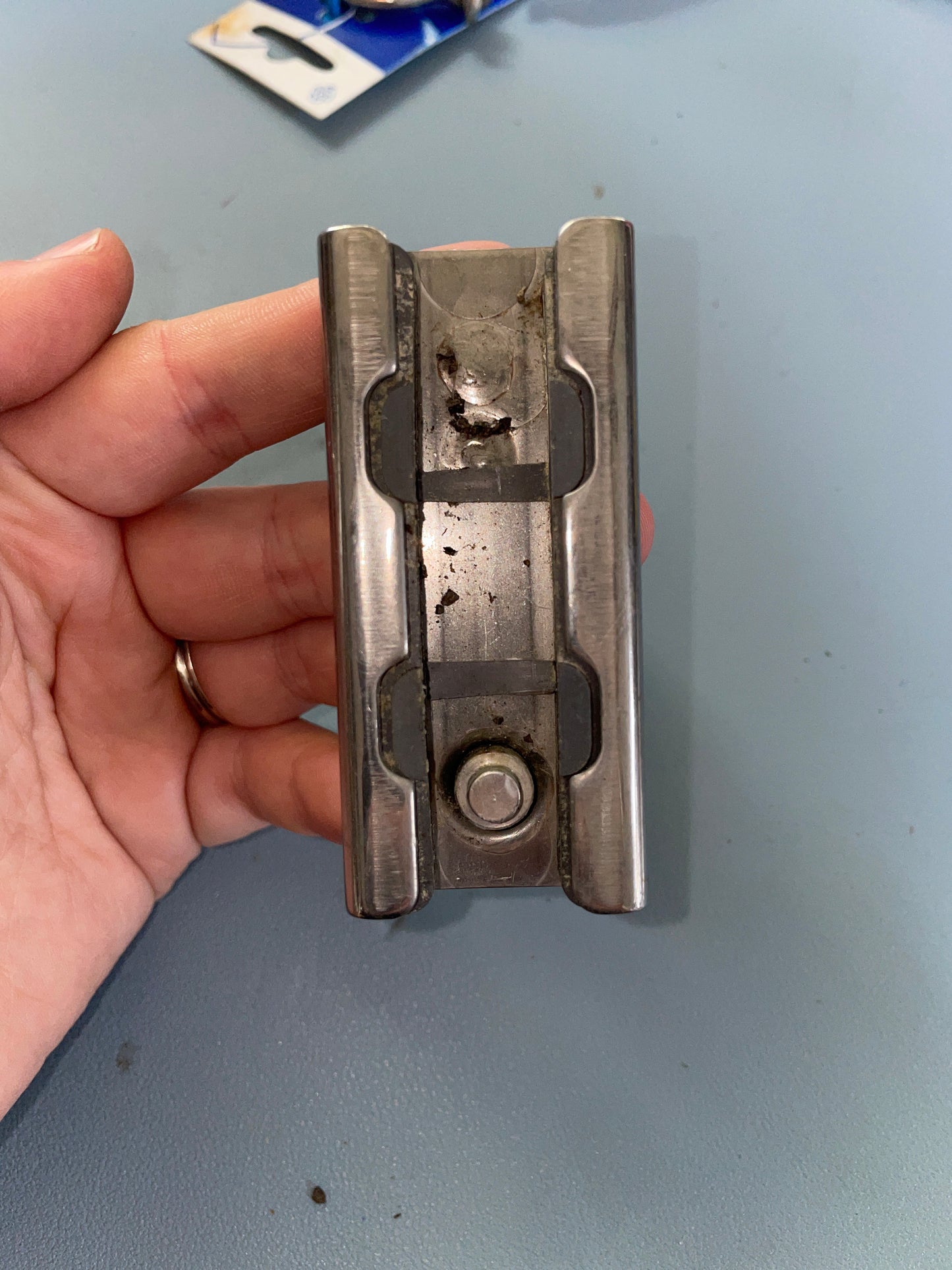 Metal bracket held in a hand against a gray background