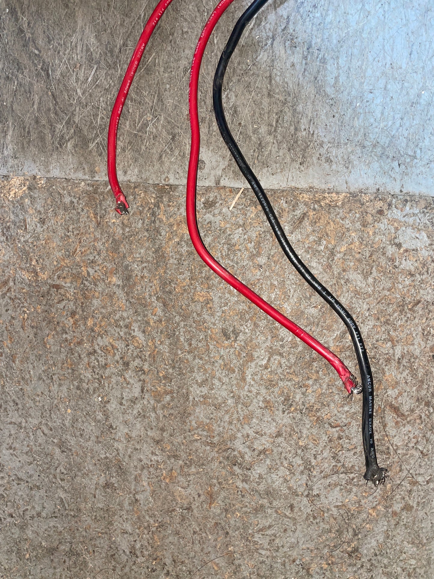 Two wires, one red and one black, on a concrete surface.